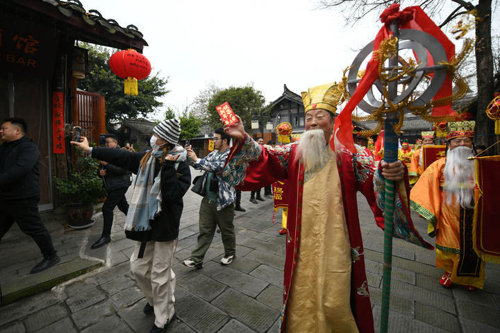 2025年1月7日，四川阆中古城启动春节文化系列活动，一名游客（左）与扮演“春节老人”的演员张忠和合影。新华社记者 胥冰洁 摄