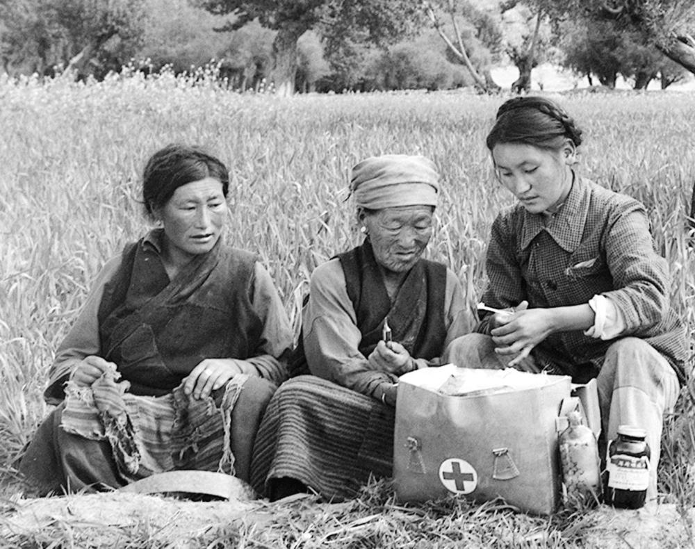 1965年9月，西藏第一文化工作队队员仓木觉（右一）在演出结束后给农民治疗。新华社记者 马竞秋 摄