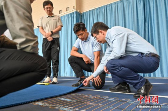 图为苏炳添在训练基地内了解数字化跑道分析系统。中新社记者 陈骥旻 摄